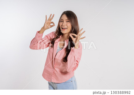 Cheerful woman making an okay gesture in a pink shirt on a white background Cheerful woman making an okay gesture in a pink shirt on a white background 130388992