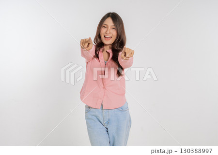Cheerful Young Woman Posing Joyfully with Outstretched Arms Against White Background 130388997