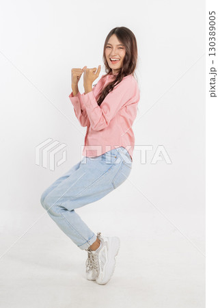 A Joyful Young Woman is Posing Playfully in Casual and Comfortable Attire 130389005