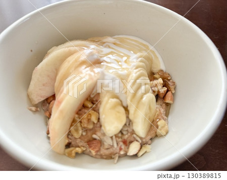 写真素材: 桃とバナナとナッツをトッピングしたオートミールボウル（朝ごはん） 130389815