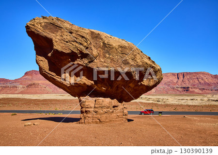 Balancing Red Boulder and SUV in Desert Landscape Eye Level Perspective Balancing Red Boulder and SUV in Desert Landscape Eye Level Perspective 130390139