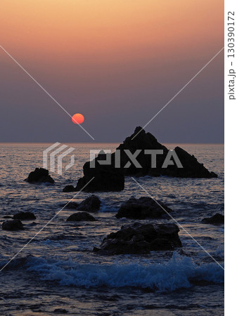 新潟県、日本海の落日。真っ赤な太陽に岩のシルエット、そして白い波が印象的で綺麗だ。 新潟県、日本海の落日。真っ赤な太陽に岩のシルエット、そして白い波が印象的で綺麗だ。 130390172