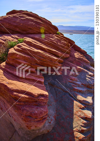 Layered Red Sandstone and Blue Lake with Vegetation at Eye Level Upward Angle 130390181