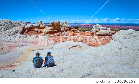 Hikers Resting on White Pocket Sandstone Vermilion Cliffs Landscape Eye Level Hikers Resting on White Pocket Sandstone Vermilion Cliffs Landscape Eye Level 130390258