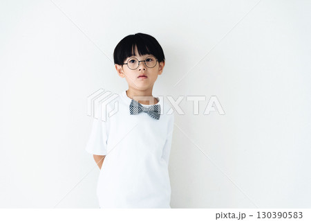 白い壁の前に立つ小学生の男の子 130390583