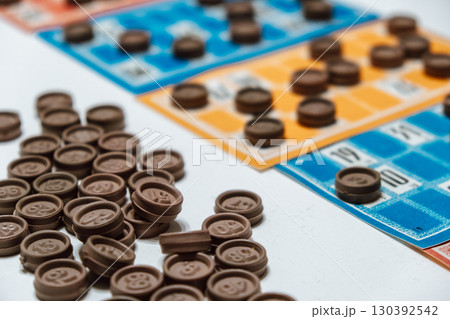 interactive bingo game with colorful cards and brown tokens on table during social event. closeup. interactive bingo game with colorful cards and brown tokens on table during social event. closeup. 130392542