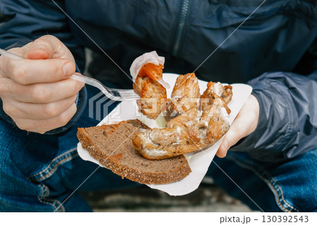 man enjoying grilled chicken and bread while sitting outdoors on cool day in park. closeup. man enjoying grilled chicken and bread while sitting outdoors on cool day in park. closeup. 130392543