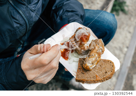 man enjoying savory snack meat on bread while seated on outdoor steps in casual setting. closeup. 130392544