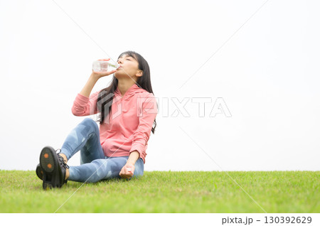 芝生の上で運動後の水分補給をする女性 130392629