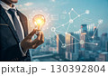 A businessman holds a glowing light bulb symbolizing innovation and new ideas, connected to a digital network representing technology and business solutions A businessman holds a glowing light bulb symbolizing innovation and new ideas, connected to a digital network representing technology and business solutions 130392804
