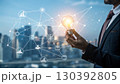 A businessman holds a glowing light bulb symbolizing innovation and new ideas, connected to a digital network representing technology and business solutions A businessman holds a glowing light bulb symbolizing innovation and new ideas, connected to a digital network representing technology and business solutions 130392805