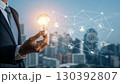 A businessman holds a glowing light bulb symbolizing innovation and new ideas, connected to a digital network representing technology and business solutions A businessman holds a glowing light bulb symbolizing innovation and new ideas, connected to a digital network representing technology and business solutions 130392807