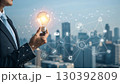 A businessman holds a glowing light bulb symbolizing innovation and new ideas, connected to a digital network representing technology and business solutions A businessman holds a glowing light bulb symbolizing innovation and new ideas, connected to a digital network representing technology and business solutions 130392809