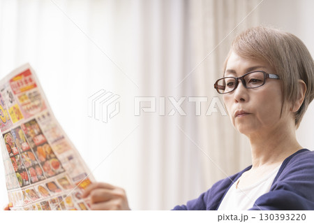 スーパーのチラシを見るシニア女性 130393220