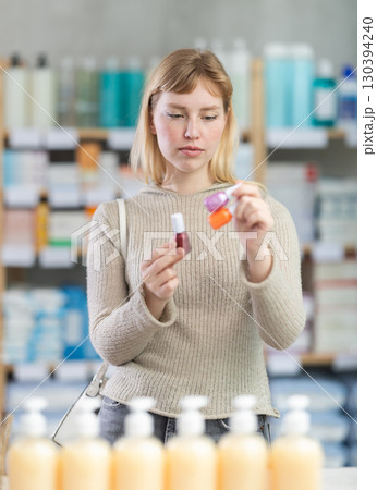 Young woman choosing nail polish in chemist's shop Young woman choosing nail polish in chemist's shop 130394240