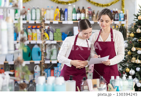 Woman seller with teen daughter, using paper report make inventory in household chemistry store Woman seller with teen daughter, using paper report make inventory in household chemistry store 130394245
