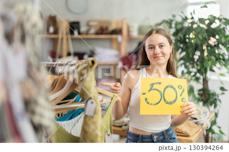 Teen girl holding discount sign in clothing store Teen girl holding discount sign in clothing store 130394264