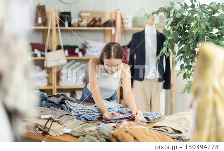 Search and selection of new jeans or shorts in a clothing store for young girl 130394278