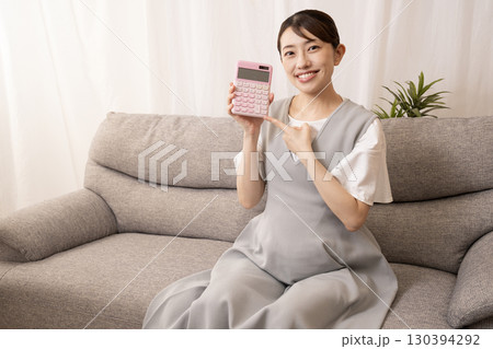 ソファーに座って電卓を持つ妊娠8ヶ月の女性 130394292