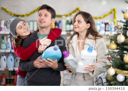Couple man and woman with daughter choosing detergent in decorated store Couple man and woman with daughter choosing detergent in decorated store 130394418