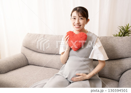 ソファーに座って赤いハートを持つ妊娠8ヶ月の女性 130394501