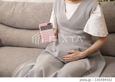 ソファーに座って電卓を持つ妊娠8ヶ月の女性 130394502