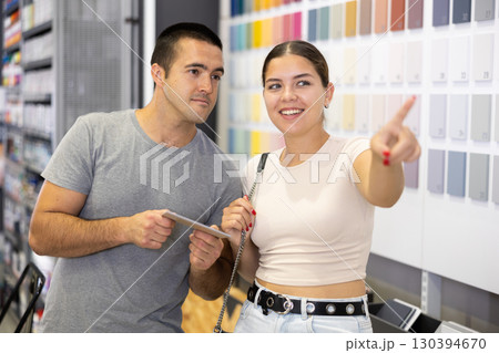 Interested couple talking while selecting painting tools in store 130394670