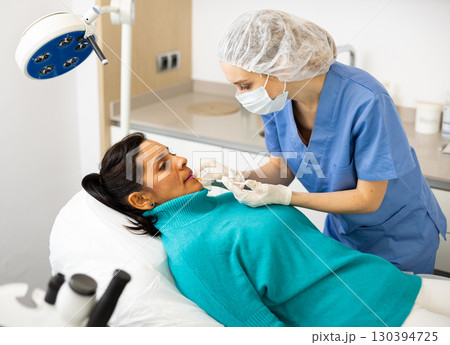 Cosmetologist giving lip injections of botulinum toxin to woman patient Cosmetologist giving lip injections of botulinum toxin to woman patient 130394725