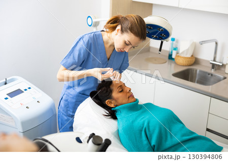 Woman patient receiving forehead injection at clinic Woman patient receiving forehead injection at clinic 130394806