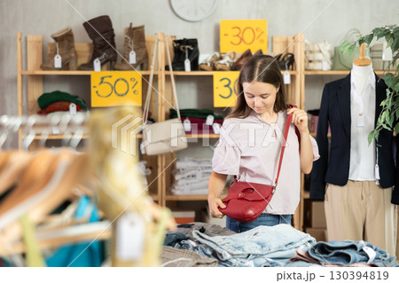 Happy teenage girl choosing handbag in clothing store Happy teenage girl choosing handbag in clothing store 130394819