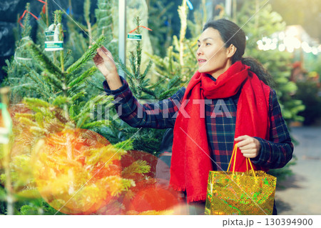 Positive woman choosing New Year's tree in christmas street fair 130394900