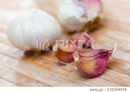 Whole garlic with separated cloves lying on a wooden table 130394976