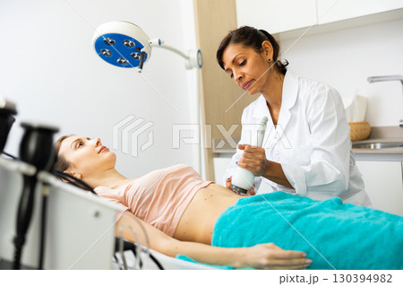 Doctor making rejuvenation electroporation procedure on abdomen 130394982