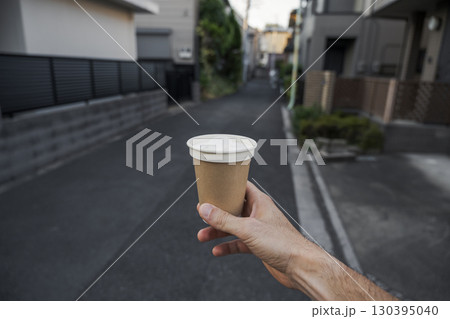 Coffee cup held up on quiet street Coffee cup held up on quiet street 130395040