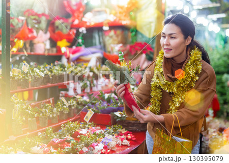 Woman choosing christmas decoration at street fair Woman choosing christmas decoration at street fair 130395079