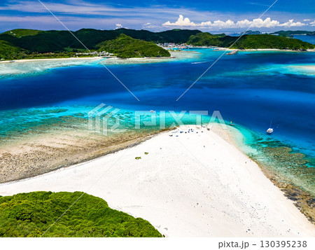 嘉比島のドローン撮影。白砂のビーチに観光客が上陸。 パラソルが立ち、ボート、サバニが停泊している。 130395238
