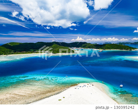 嘉比島のドローン撮影。白砂のビーチに観光客が上陸。 パラソルが立ち、ボート、サバニが停泊している。 130395242