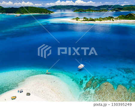 嘉比島のドローン撮影。白砂のビーチに観光客が上陸。 パラソルが立ち、ボート、サバニが停泊している。 嘉比島のドローン撮影。白砂のビーチに観光客が上陸。 パラソルが立ち、ボート、サバニが停泊している。 130395249