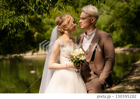 Newlyweds share a tender moment by the riverside in a serene natural setting 130395282