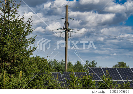 Solar Panels Under Power Lines with Trees and Cloudy Sky 130395695