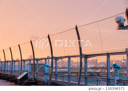 夕焼けの羽田空港のデッキ。 離発着する旅客機と夕暮れの東京の町並みが見える。2025 夕焼けの羽田空港のデッキ。 離発着する旅客機と夕暮れの東京の町並みが見える。2025 130396571