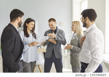 Group of colleagues standing in the office and laughing at a funny joke together Group of colleagues standing in the office and laughing at a funny joke together 130396685