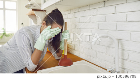 Sad Woman Facing Sink Blockage with Plunger 130396709