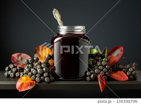 Chokeberry jam and fresh berries with leaves. Chokeberry jam and fresh berries with leaves. 130398706