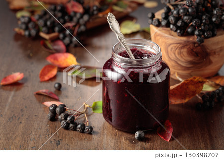 Chokeberry jam and fresh berries on an old wooden table. Chokeberry jam and fresh berries on an old wooden table. 130398707