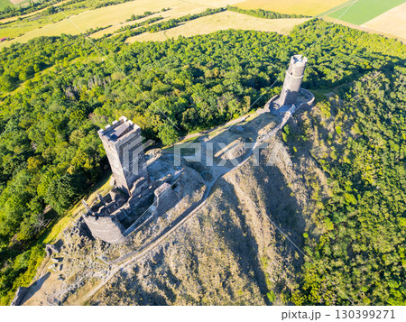 Perched atop a hill, the ruins of Hazmburk Castle showcase medieval architecture amidst lush greenery in Czechia's Central Bohemian Uplands, providing stunning views of the surrounding landscape. Perched atop a hill, the ruins of Hazmburk Castle showcase medieval architecture amidst lush greenery in Czechia's Central Bohemian Uplands, providing stunning views of the surrounding landscape. 130399271