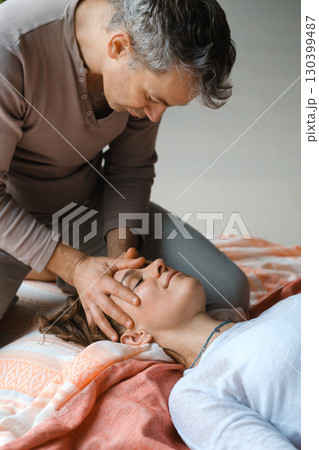 Relaxing massage therapy session focusing on facial techniques in a serene indoor setting during daylight hours 130399487