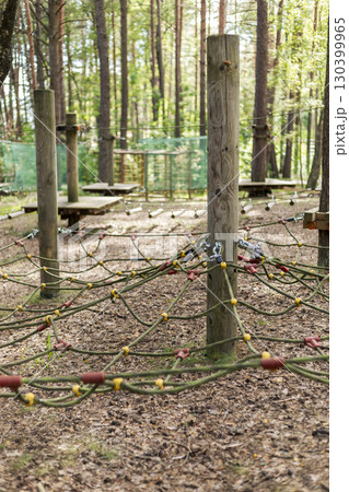 A vibrant outdoor tree climbing park features intricate climbing structures and safety nets nestled among tall trees, creating an adventurous atmosphere for exploration in nature A vibrant outdoor tree climbing park features intricate climbing structures and safety nets nestled among tall trees, creating an adventurous atmosphere for exploration in nature 130399965