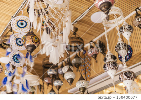 Various handmade ornaments and decorations dangle from the ceiling, displaying intricate designs and vibrant colors in a lively marketplace that celebrates local craftsmanship 130400677