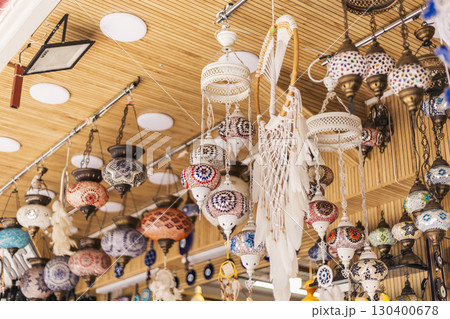 A variety of intricately designed lanterns and crafts hang from the ceiling in a bustling market in Morocco, attracting shoppers with their vivid colors and unique patterns 130400678